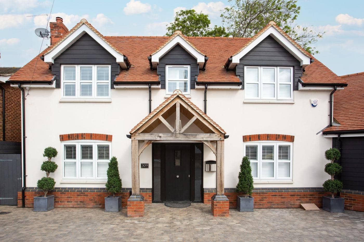 The front of a new build home with an oak porch and a black front door The front of a new build home with an oak porch and a black front door